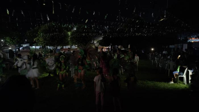 Ao lado da Amazonas Energia, crianças brincam quermesse com luz de celulares, em Parintins 
